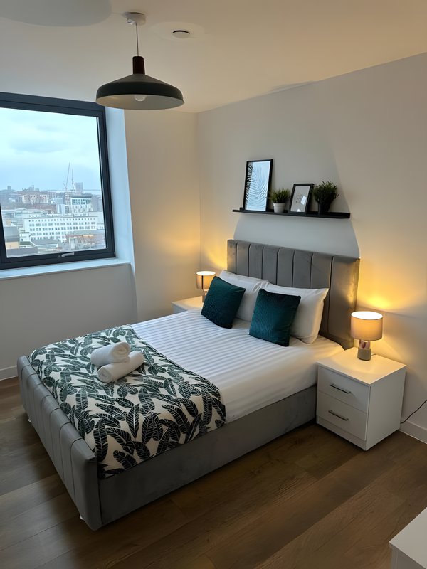 Modern bedroom with double bed, pendant light, wall-mounted headboard, and city view window