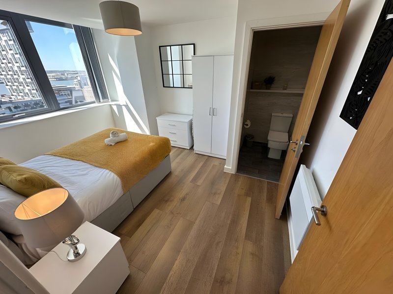 Modern bedroom with single bed, wooden flooring, pendant lamp and city view window