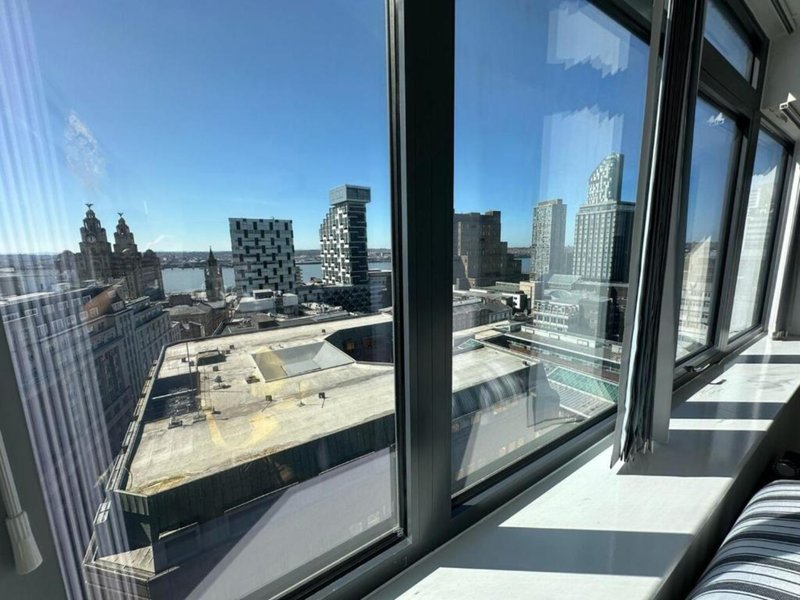 High-rise apartment with floor-to-ceiling windows overlooking urban cityscape and river