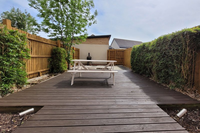 Modern backyard terrace with composite decking, white bench seating, and wooden fencing