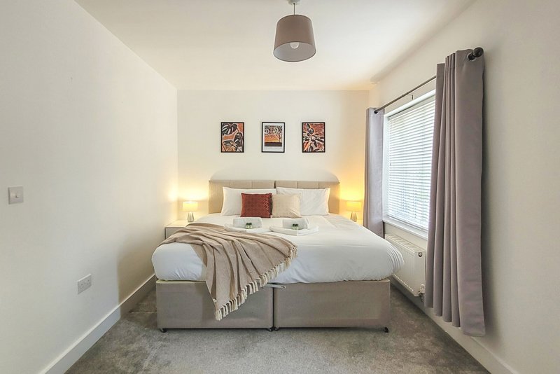 Bright bedroom with double bed, bedside lamps, framed wall art and window