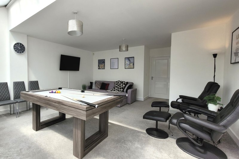 Modern recreation room with pool table, gaming chairs, sofa and wall-mounted TV