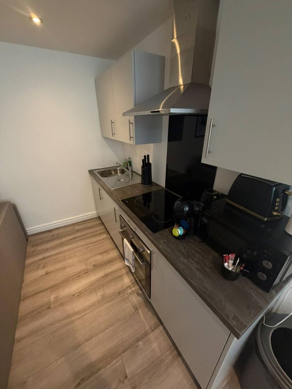 Modern galley kitchen with white cabinets, black countertop, stainless steel sink and appliances