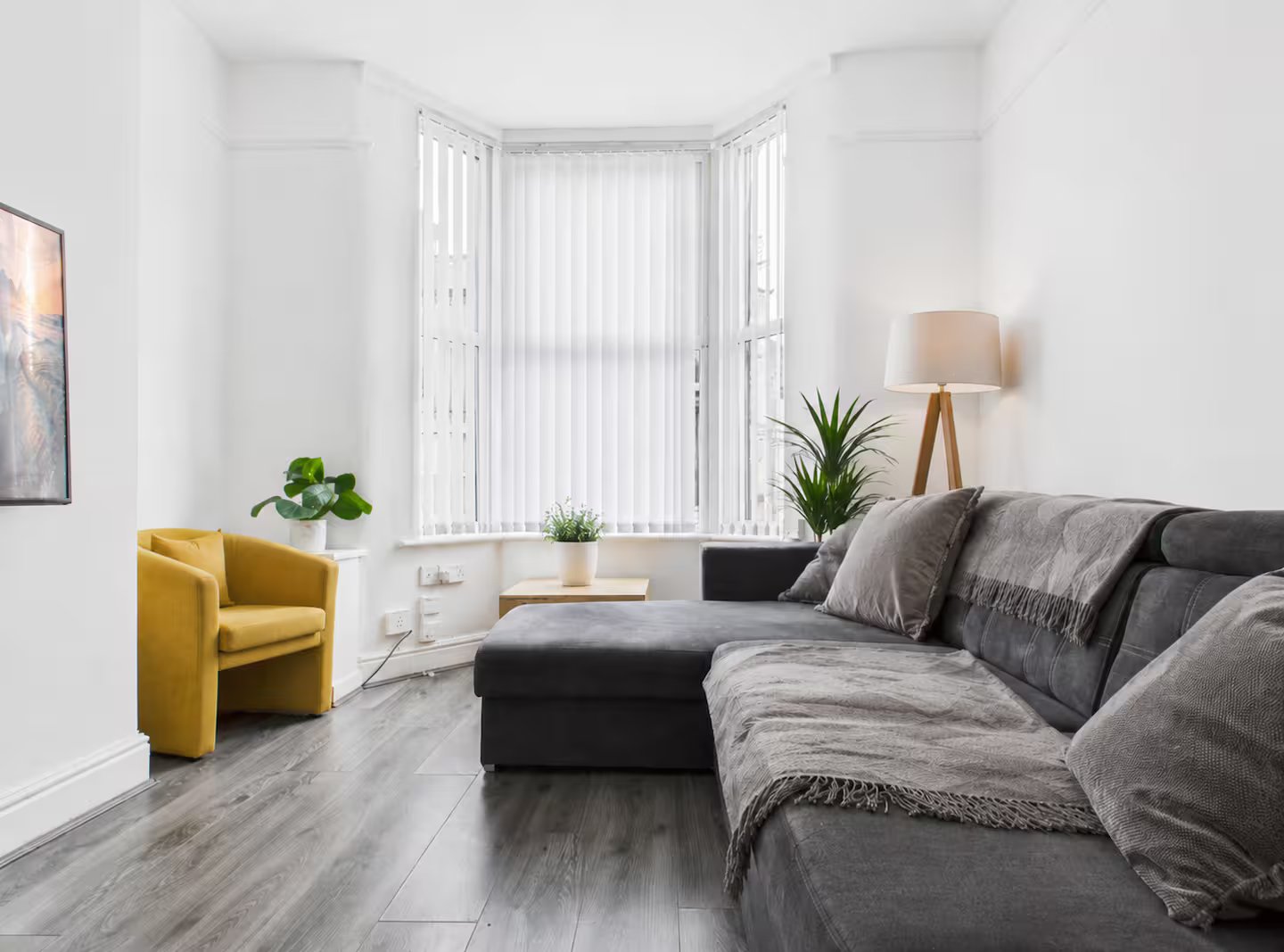 Bright modern living room with gray sofa, yellow armchair, wooden lamp, and plants