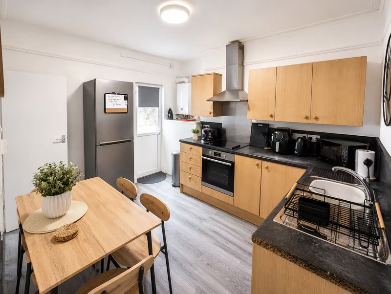 Modern kitchen with wooden cabinets, black countertop, stainless steel appliances and dining table