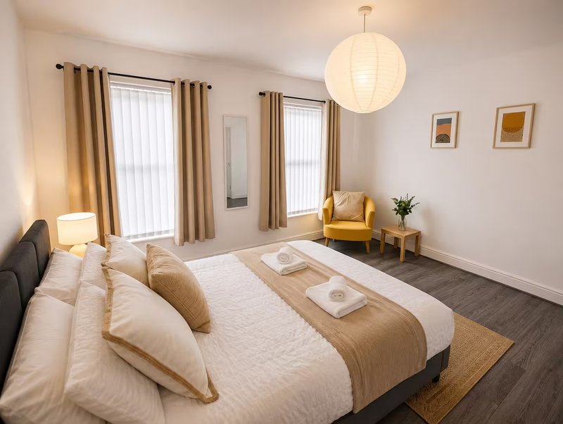 Modern bedroom with double bed, pendant lamp, armchair, and floor-to-ceiling windows