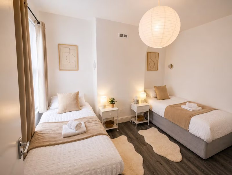 Twin bedroom with two single beds, pendant light, bedside tables and warm neutral décor