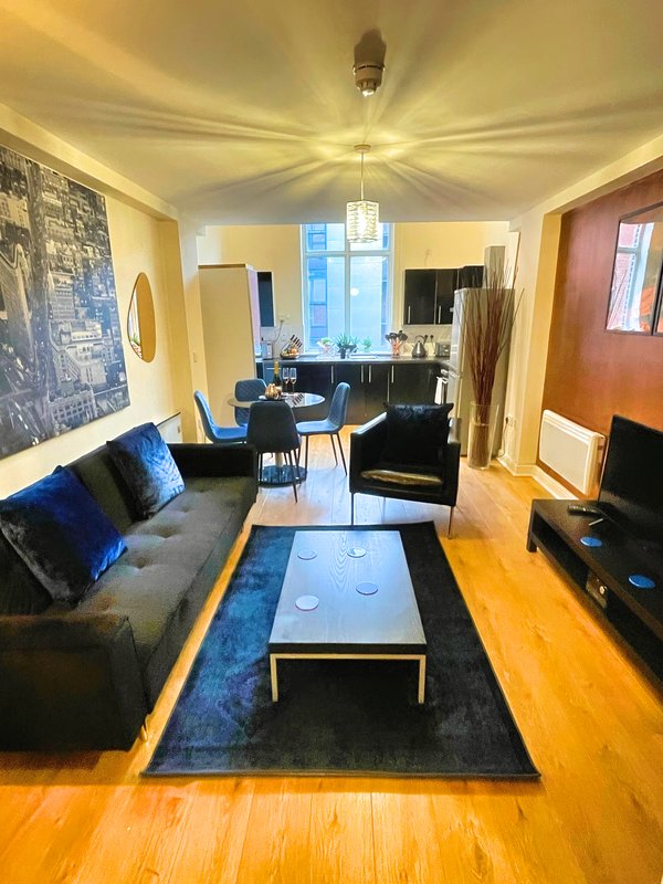 Open-plan living room with sofa, coffee table, dining area and kitchen visible