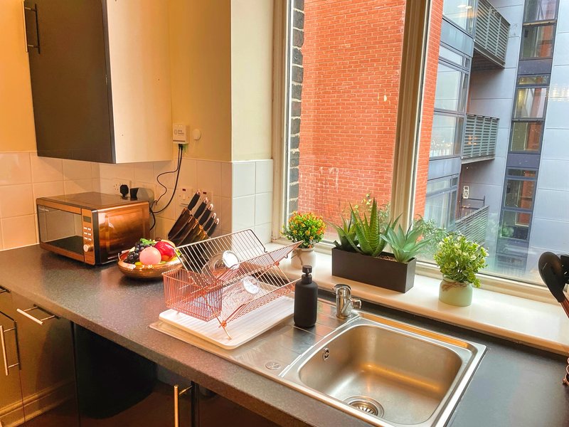 Modern kitchen with sink, countertop, plants, microwave and city views from window