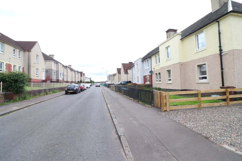 Residential street with semi-detached houses, driveways, fencing and parked cars