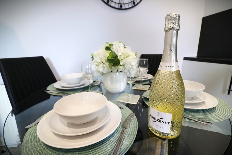 Formal dining table set with white plates, champagne bottle, white flowers and place settings