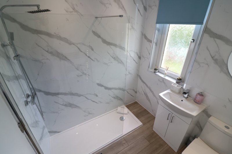 Modern bathroom with marble-effect tiles, shower enclosure, sink vanity and window