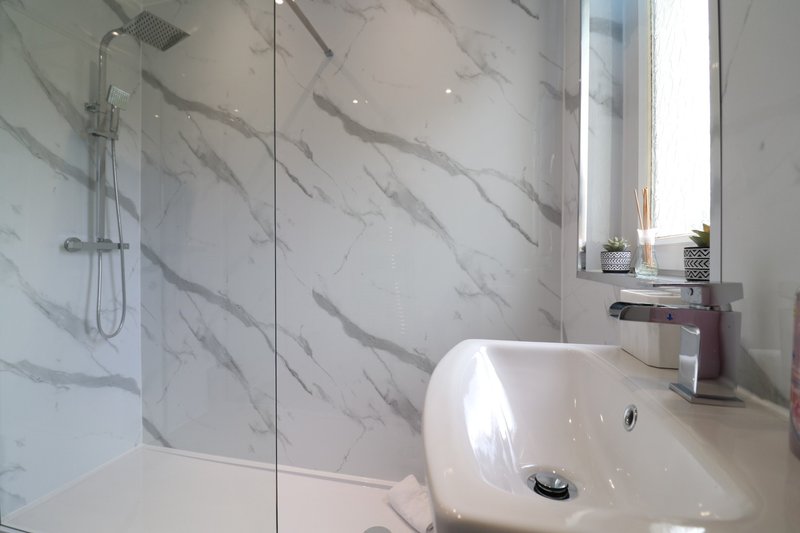 Modern bathroom with marble-effect tiling, glass shower enclosure, white sink and chrome fixtures