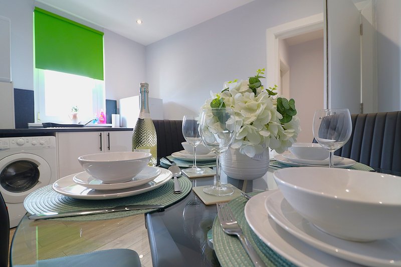Modern dining area with place settings, champagne bottle, white flowers and washing machine visible