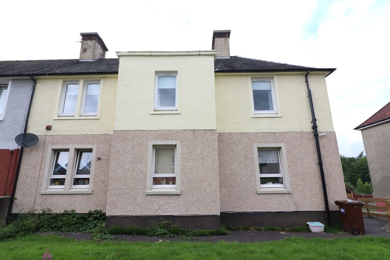 Two-storey detached house with cream and pink render, multiple windows and chimneys