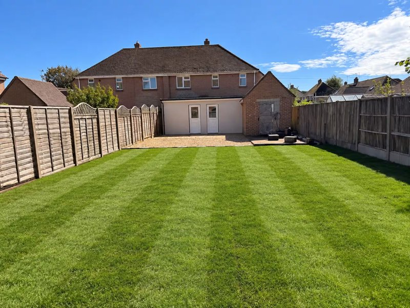 Brick house with manicured lawn, wooden fences, and clear blue sky