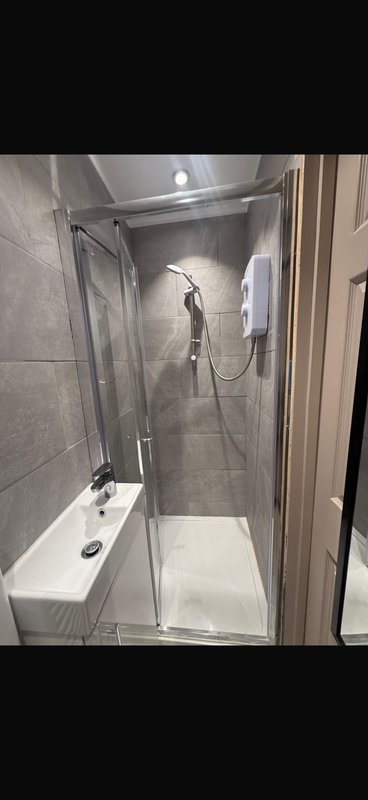 Modern bathroom shower enclosure with grey tile walls and white base tray