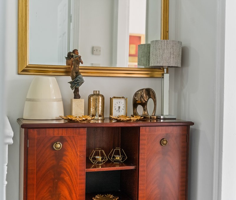 Wooden dresser with mirror, lamp, decorative objects and clock display