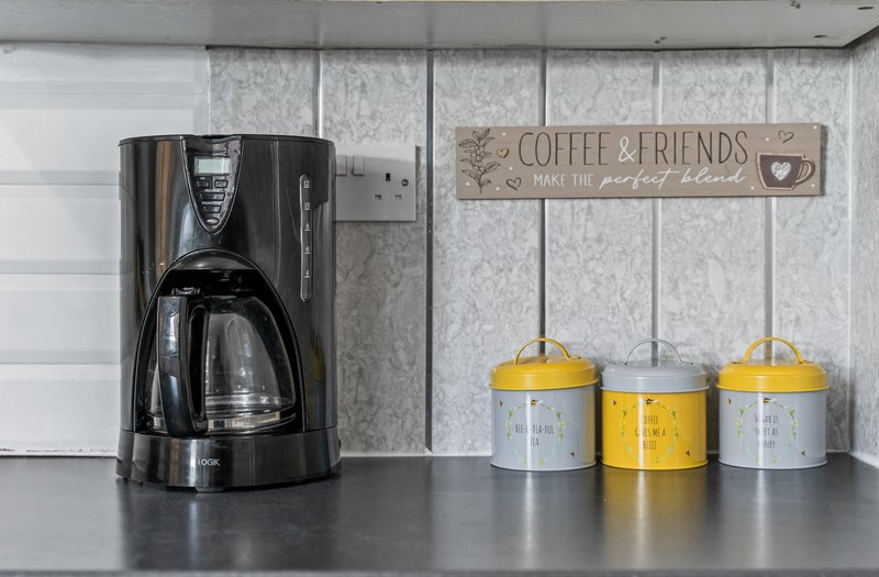Kitchen counter with coffee maker, yellow storage containers, and decorative wall sign