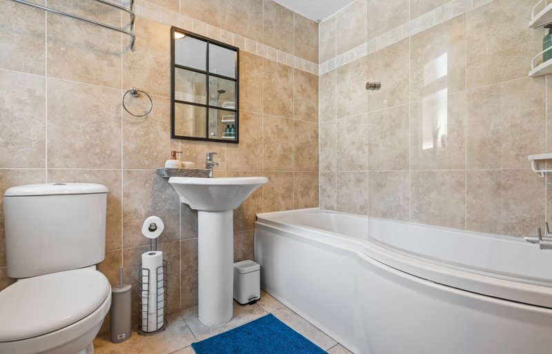 Bathroom with toilet, pedestal sink, bathtub, tiled walls and mirror cabinet