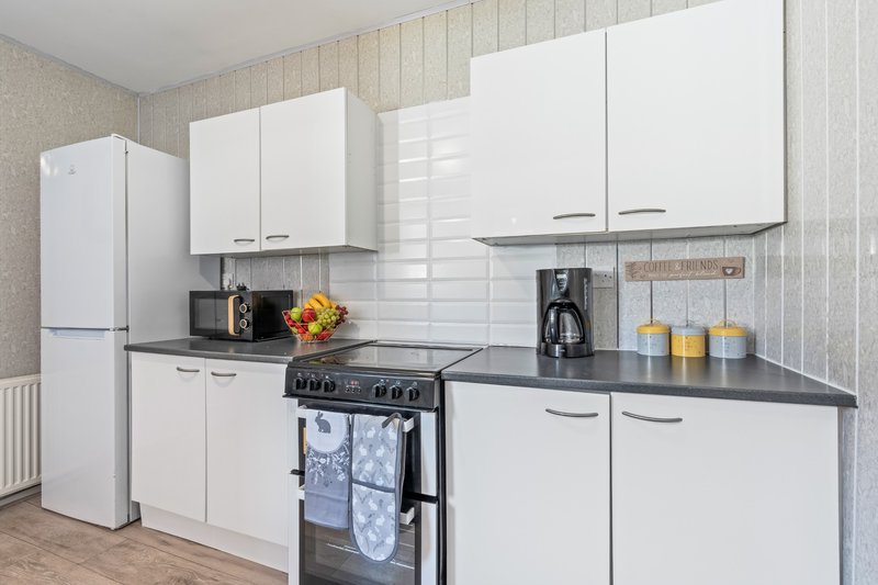Modern kitchen with white cabinetry, black countertop, black range cooker and stainless steel appliances