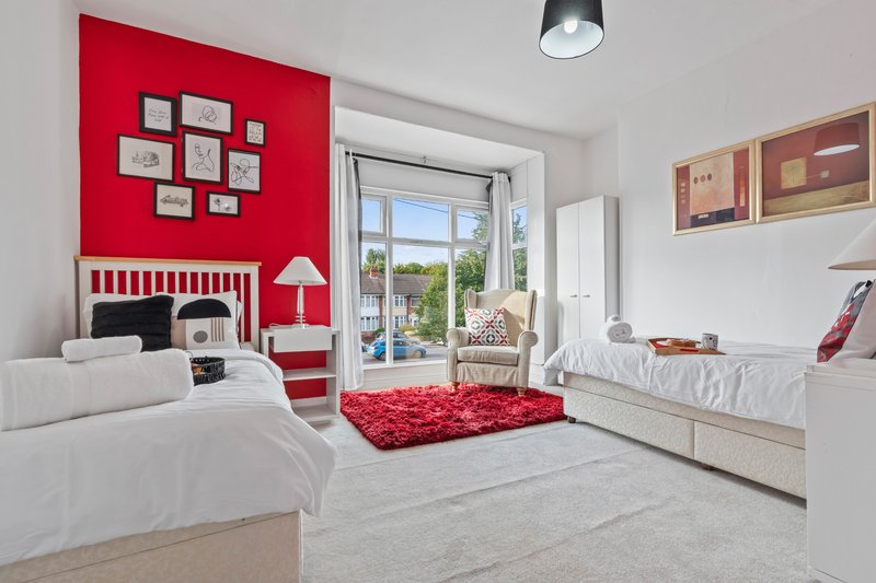 Bright children's bedroom with twin beds, red feature wall, and red shag rug