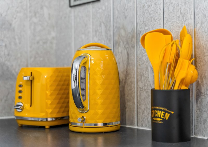 Kitchen counter with yellow kettle, toaster, and utensil holder with kitchen tools