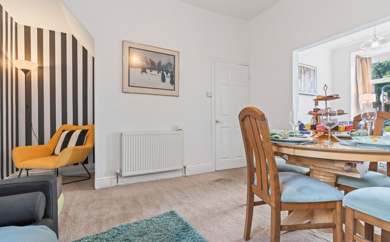 Open-plan living and dining area with yellow armchair, wooden dining table, and striped curtains