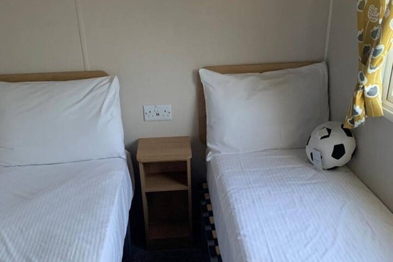 Twin bedroom with white pillows, striped bedding, wooden bedside table and soccer ball decoration