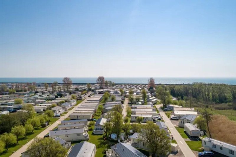 Aerial view of residential neighborhood with houses, trees, roads and distant water