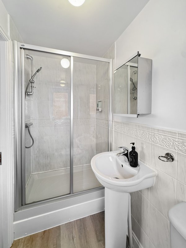 Modern bathroom with shower enclosure, pedestal sink, mirror cabinet and wood-effect flooring
