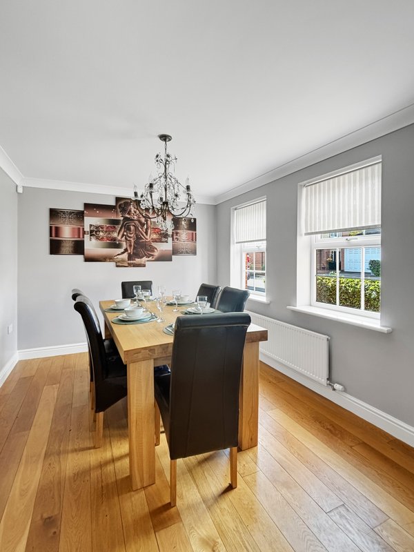 Dining room with wooden table, black chairs, chandelier and wall art