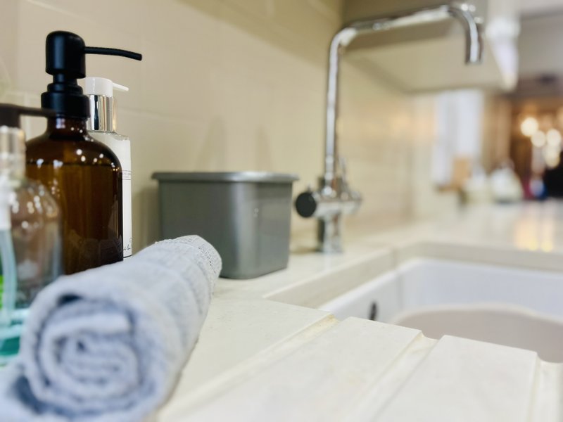 Bathroom sink counter with soap dispenser, towel, and faucet