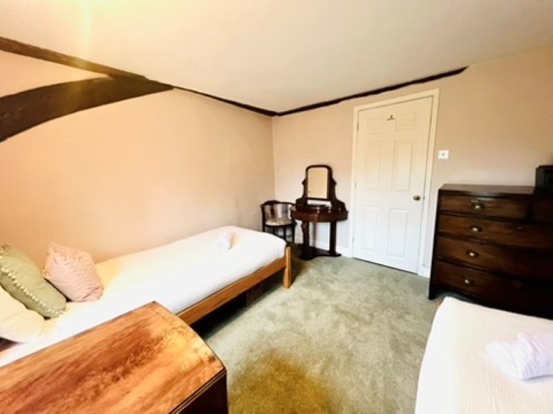 Bedroom with two single beds, wooden furniture, dresser, and white doors