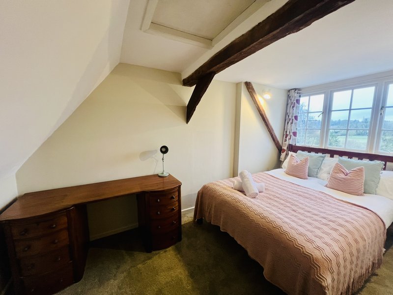 Attic bedroom with double bed, wooden desk, exposed beam and countryside views