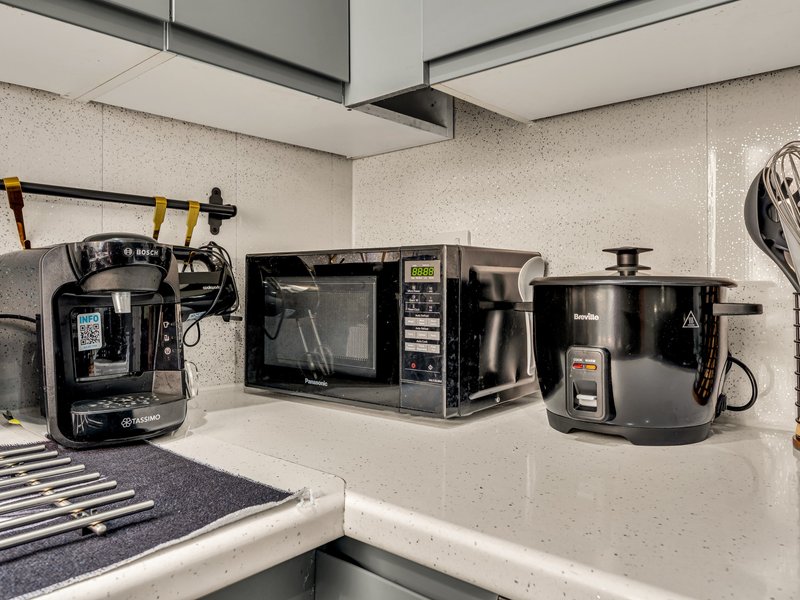 Kitchen countertop with black appliances including coffee maker, microwave, and slow cooker