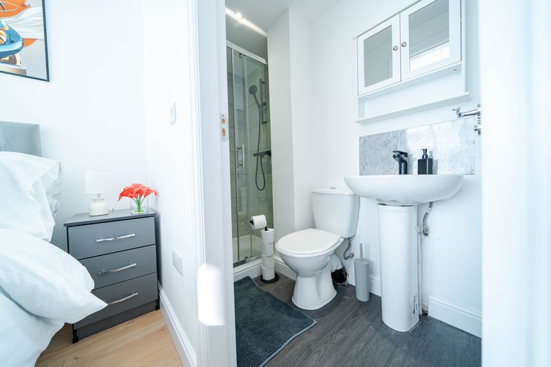 Compact ensuite bathroom with toilet, sink, shower cubicle and storage cabinet