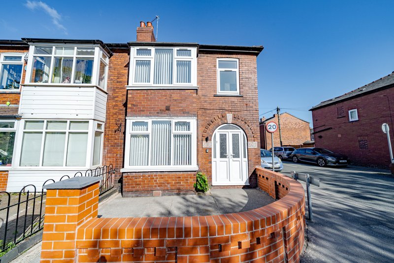 Brick semi-detached house with white door, driveway and front garden fence