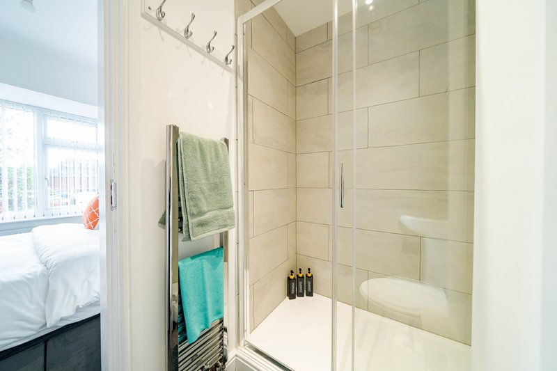 Modern bathroom with walk-in shower, cream tiles, heated towel rail and window