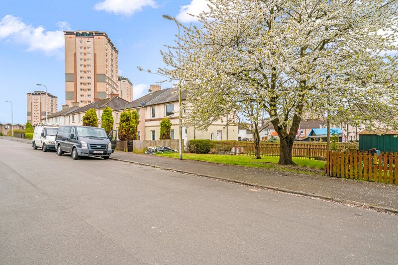 Residential street with parked vehicles, brick apartment buildings, and blooming trees