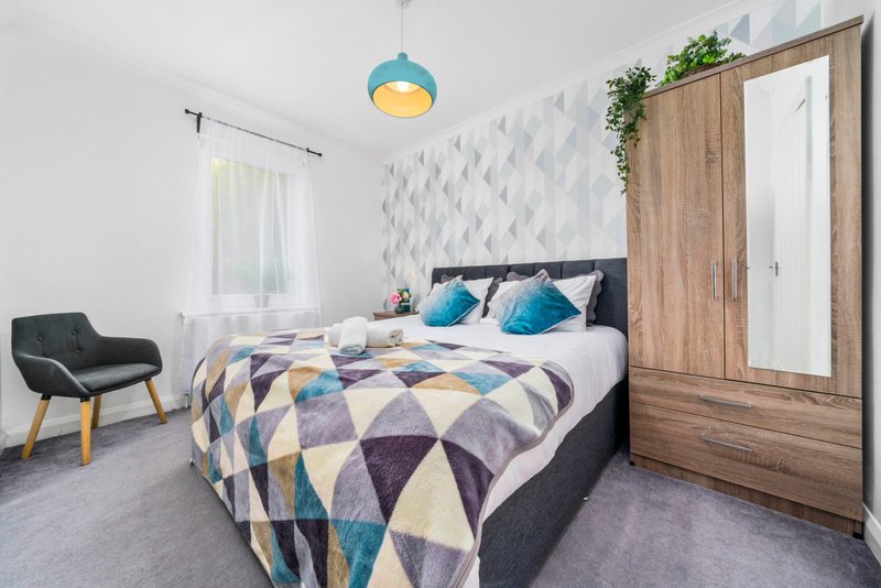 Modern bedroom with double bed, geometric bedding, blue pendant light and wooden wardrobe