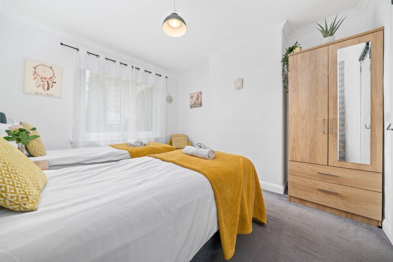 Bright bedroom with double bed, wooden wardrobe, window seat and yellow accent pillows