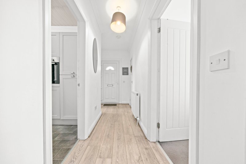 Bright hallway with white doors, wooden flooring, pendant light and wall switches