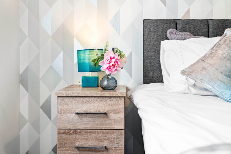 Bedroom nightstand with pink flowers, blue decorative box, and bedside lamp
