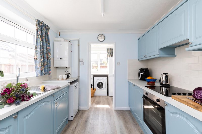 Modern kitchen with light blue cabinetry, stainless steel appliances, and wooden worktops