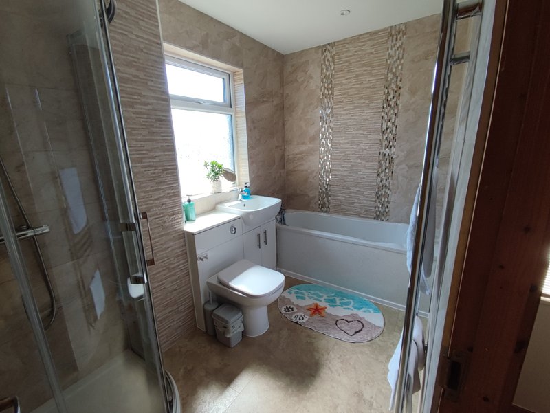 Modern bathroom with shower enclosure, toilet, sink and window with natural light