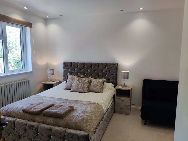 Modern bedroom with double bed, tufted headboard, bedside tables, and window with natural light