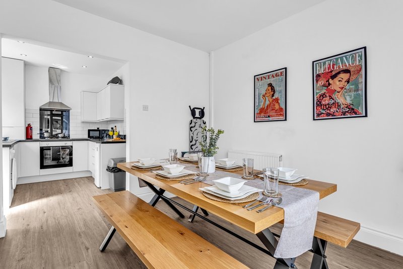 Modern open-plan kitchen and dining area with wooden table, bench seating, and wall art