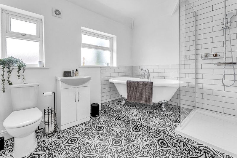 Modern bathroom with toilet, sink, freestanding bathtub, shower enclosure and patterned floor tiles