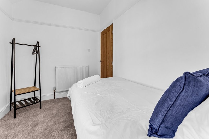 Bright bedroom with double bed, wooden door, clothes rail and radiator